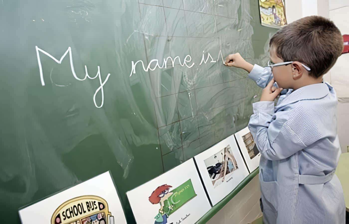 Niño escribe inglés en la pizarra del colegio